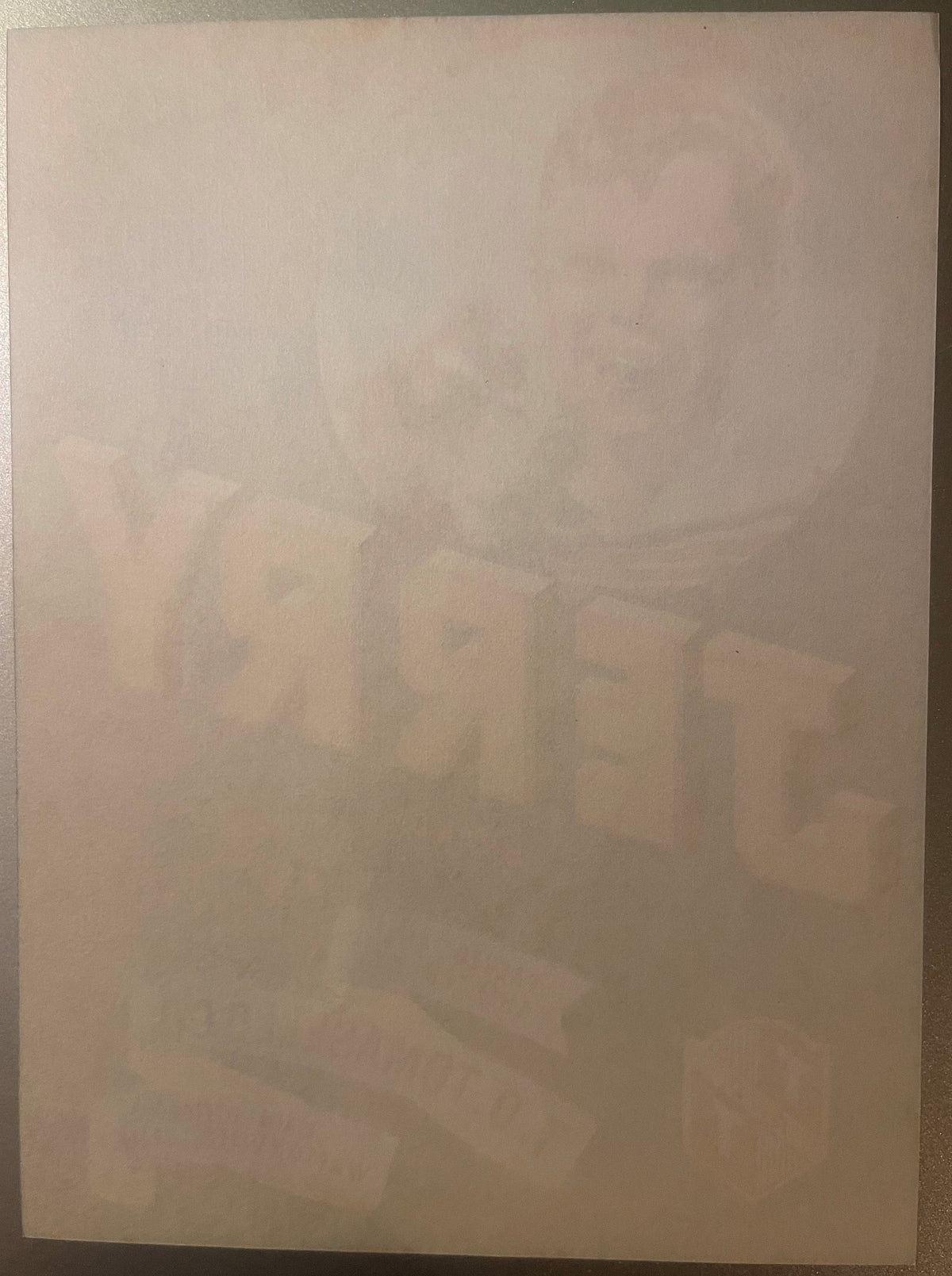 Faded vintage crate label with dog illustration and text, laid flat on tan surface, heavily aged and difficult to read