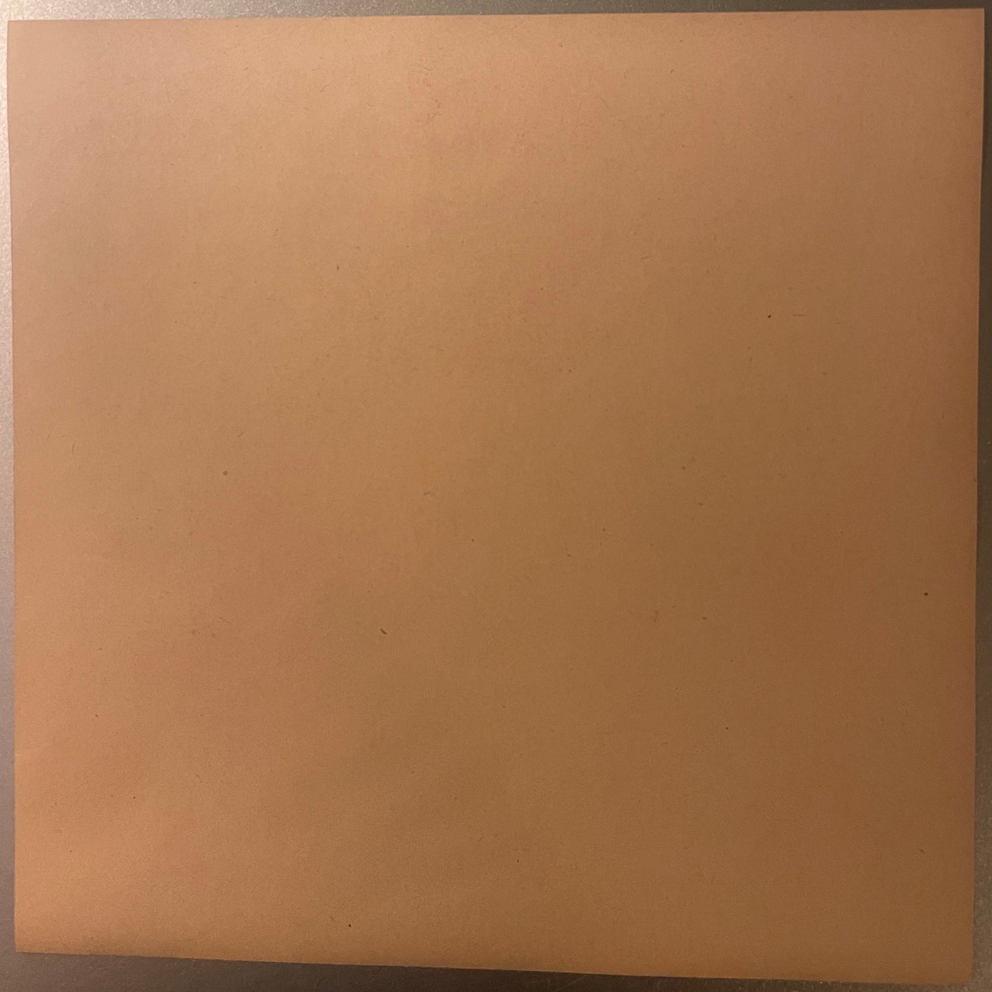 Blank tan-colored vintage crate label with subtle texture and minor spots, photographed flat against gray background