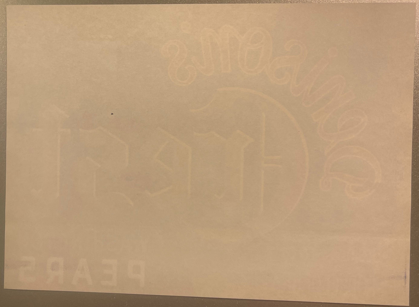 Cream-colored vintage pear crate label with faint embossed imagery of pears and decorative elements, photographed flat agains