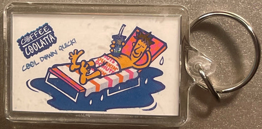 Vintage Dunkin' Donuts Coffee Coolatta keychain fob in clear plastic case with colorful cartoon character on striped lounger,