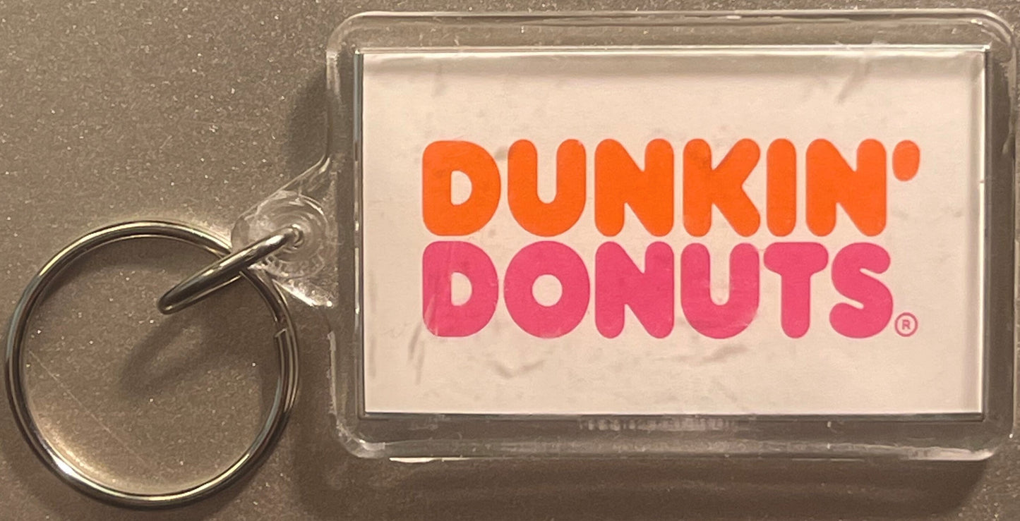 Vintage Dunkin' Donuts keychain fob with orange and pink logo on clear plastic card with metal split ring against gray backgr