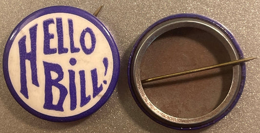 Front and back views of a purple and white celluloid pinback button reading "HELLO BILL!" in block letters, with metal pin vi
