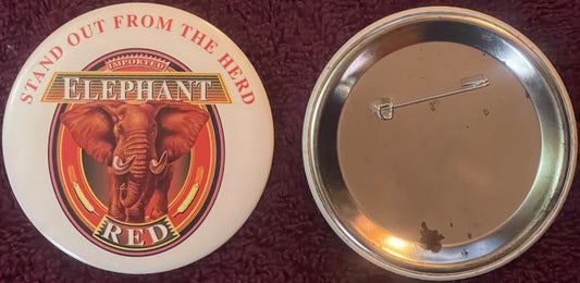 Front and back of vintage Elephant Red beer pin badge showing red elephant head logo with "Stand Out From The Herd" text and