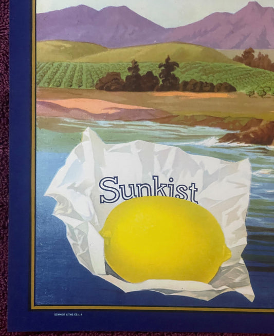 Vintage Sunkist lemon crate label featuring a bright yellow lemon in white petals, with rural landscape and mountains in back
