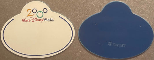 Front and back of a cream and blue Mickey-shaped Disney World 2000 cast member badge with "Walt Disney World" text and Disney