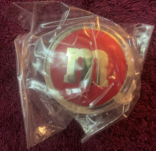 Red and yellow M&M's yo-yo in clear plastic packaging on burgundy fabric, showing both sides of the double-sided toy