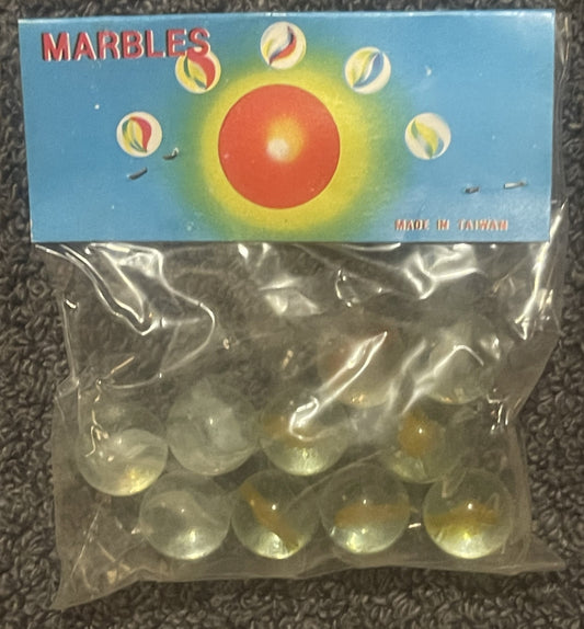 Unopened plastic bag of clear cat's eye marbles with blue, yellow and red label reading "MARBLES" and "MADE IN TAIWAN," displ