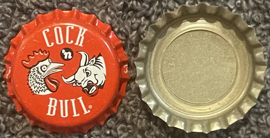 Red and cream bottle cap with rooster and bull graphics, "COCK 'n BULL" text, shown front and back view on textured surface
