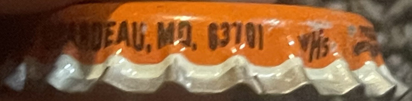 Close-up of orange and white ridged cork bottle cap with embossed text, shown at an angle