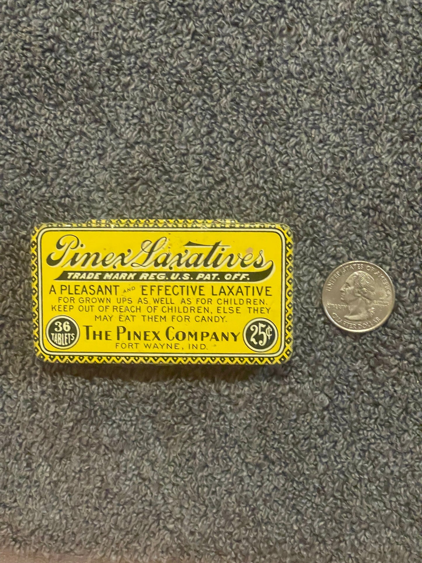Vintage yellow Pinex Laxatives tin from Fort Wayne, Indiana, displayed next to a quarter for scale