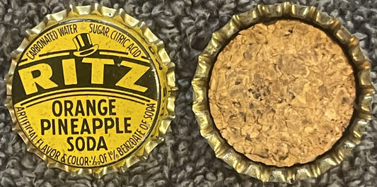 Two views of a yellow and gold Ritz Orange Pineapple Soda bottle cap from St. Louis showing the printed label side and cork i