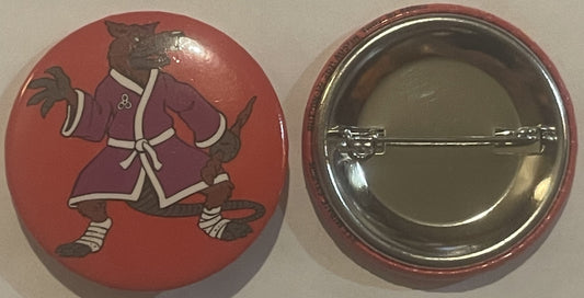 Front and back of red circular pinback button featuring brown cartoon rat character in purple robe with white trim against re
