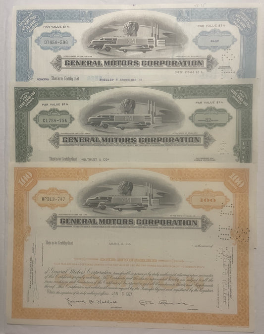Three General Motors Corporation stock certificates from the 1950s-80s featuring streamlined locomotive vignettes, displayed