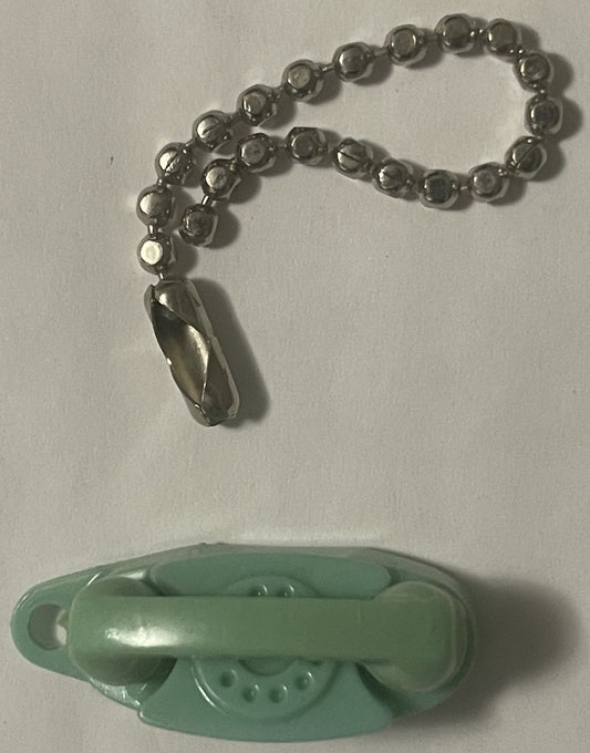 Vintage green plastic rotary phone keychain with metal beaded chain and teardrop charm, displayed above matching phone base o