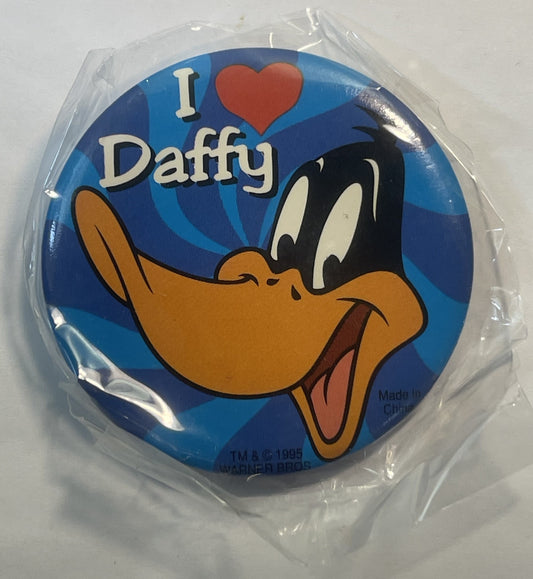 Unopened circular pin in clear plastic packaging featuring Daffy Duck cartoon character with "I ❤ Daffy" text on blue backgro