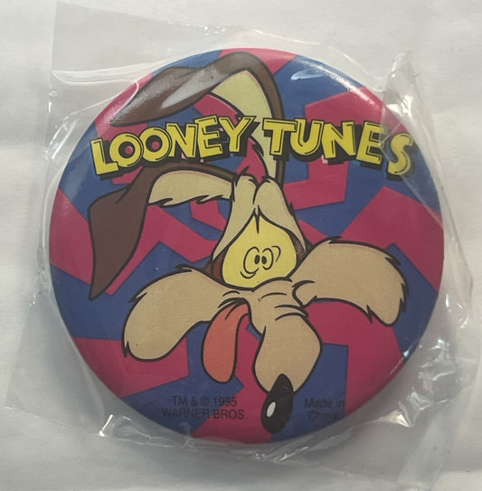 Unopened circular pin in clear plastic package featuring Wile E. Coyote cartoon character on red and blue checkered backgroun