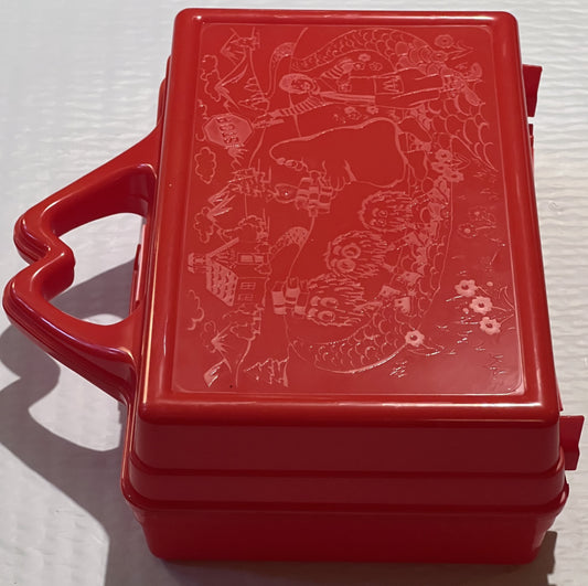 Bright red plastic lunch box with heart-shaped handle and embossed McDonaldland characters and scenes on lid, photographed fr