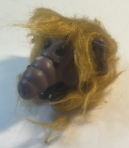 Vintage ALF finger puppet with golden-yellow fuzzy hair and dark brown rubber face, shown in close-up against white backgroun