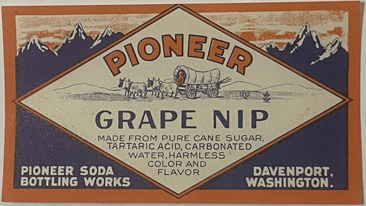 Vintage Pioneer Grape Nip soda label from Davenport, Washington, featuring mountains, covered wagon, and brown/cream diamond-