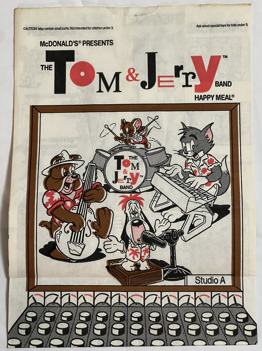 Vintage McDonald's Happy Meal bag front featuring Tom & Jerry Band illustration with cartoon characters playing instruments,