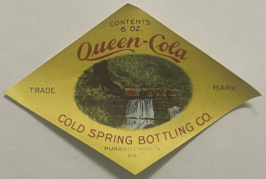 Diamond-shaped yellow label for Queen-Cola from Cold Spring Bottling Co., Punxsutawney PA, with forest spring image, 6 oz con