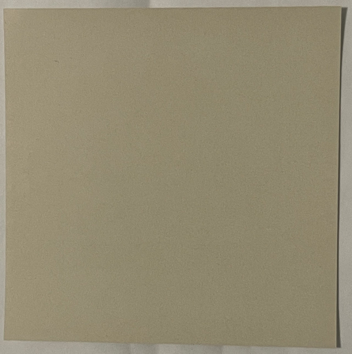 Blank tan cardboard or paper surface with a vertical crease on the right edge, photographed flat