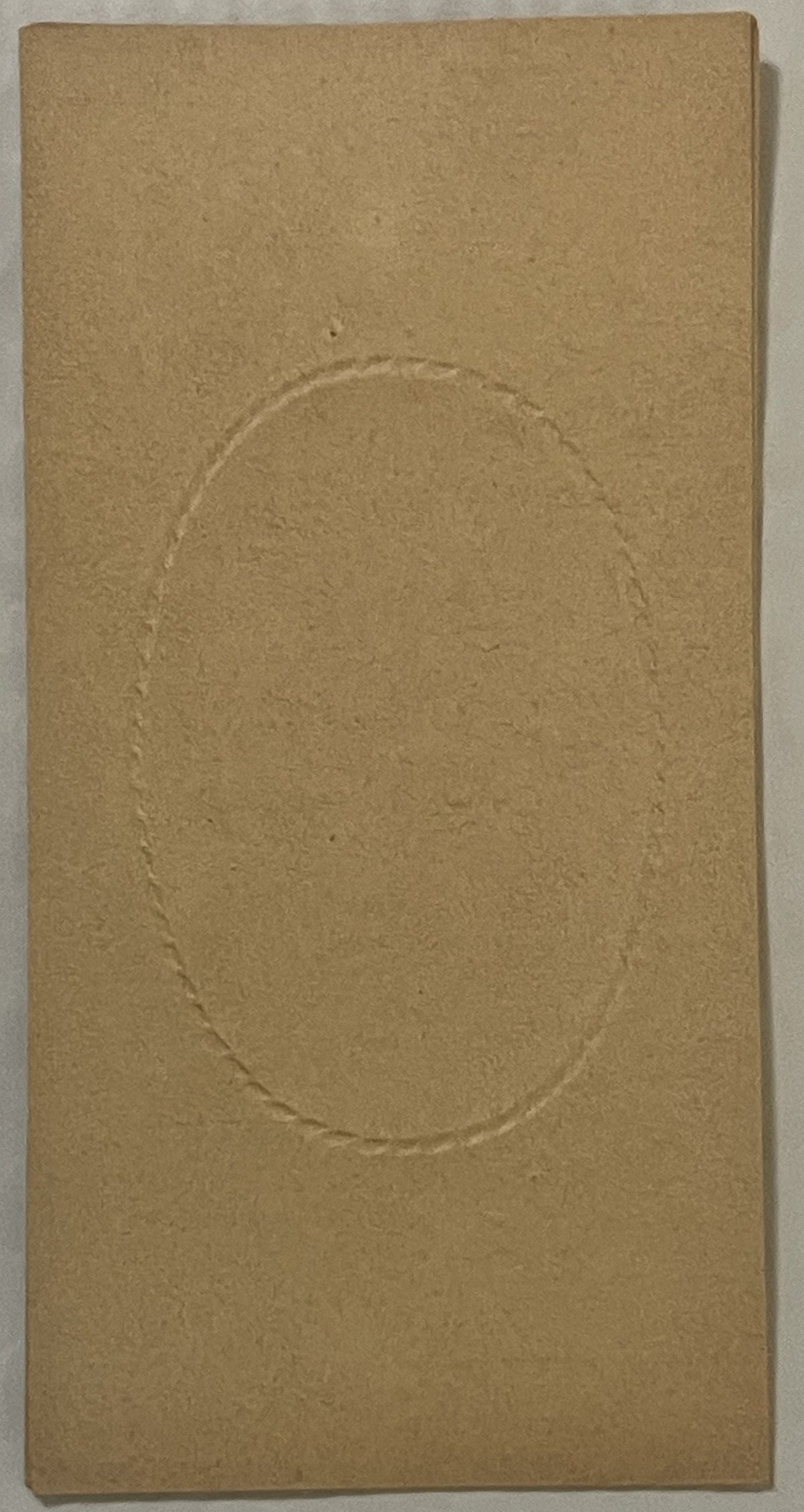Tan cardboard box insert with embossed oval frame, shown flat against white surface