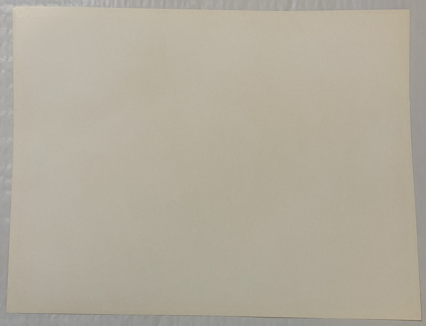 Blank cream-colored page or print surface photographed flat against gray textured background