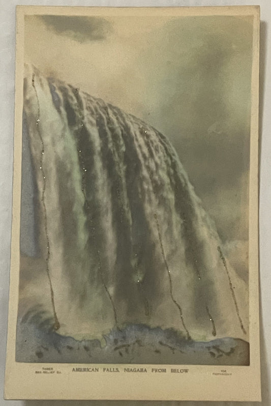 Sepia-toned vintage postcard showing American Falls at Niagara from below, with cascading water and mist, printed text at bot