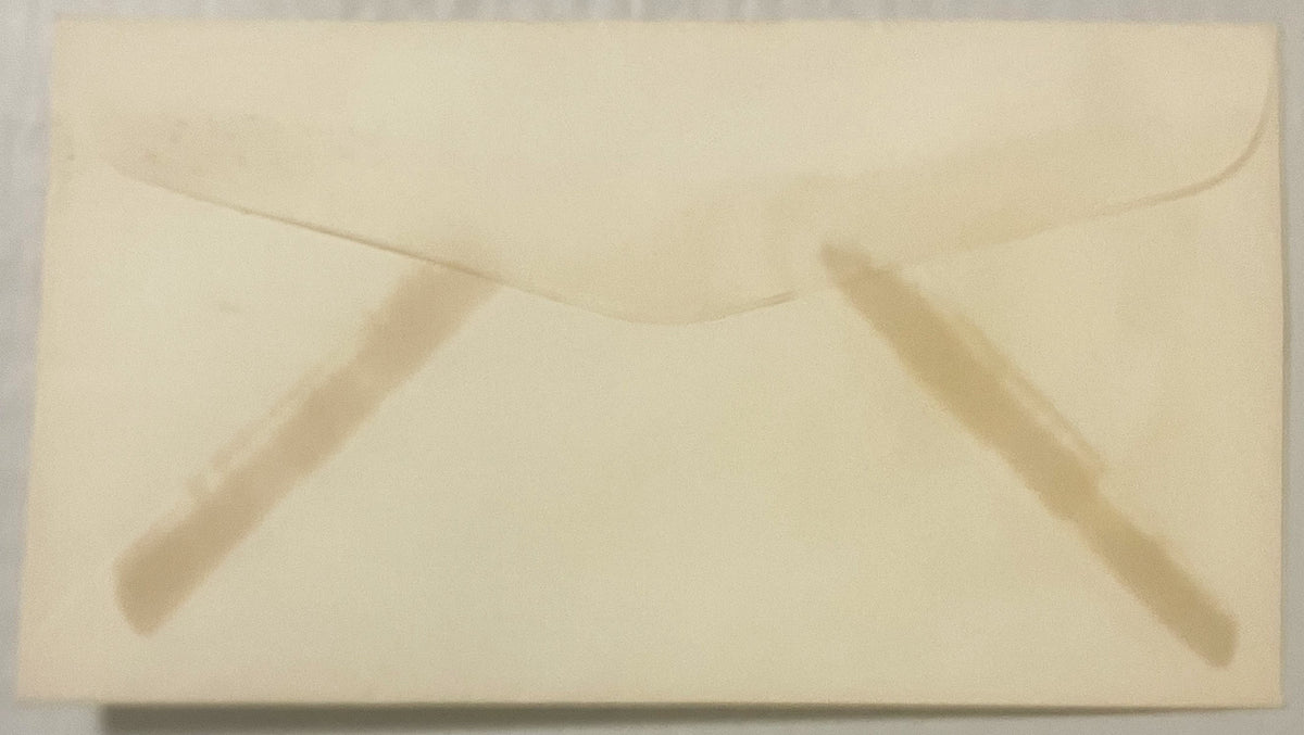 Cream-colored vintage envelope with embossed flap and faint impressions of text, photographed flat from above