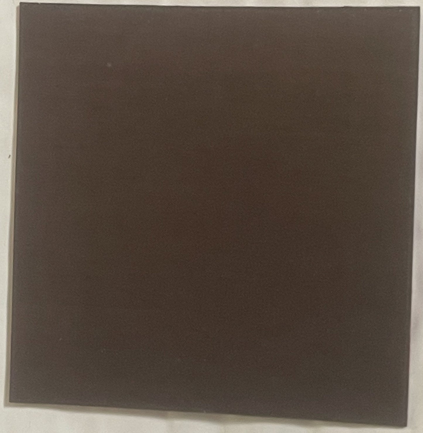 Dark brown square refrigerator magnet photographed flat against white background, appears blank or unmarked on visible side