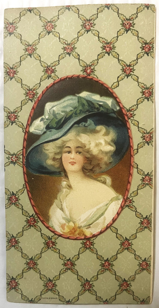 Edwardian chromolithograph insert featuring a woman in profile wearing a large black hat with blue plumes, set in red oval fr