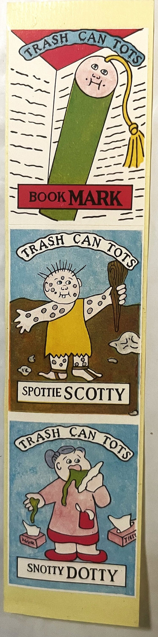 Three vintage "Trash Can Tots" sticker panels featuring cartoon characters: a green wrapped figure labeled "Book Mark," a spo