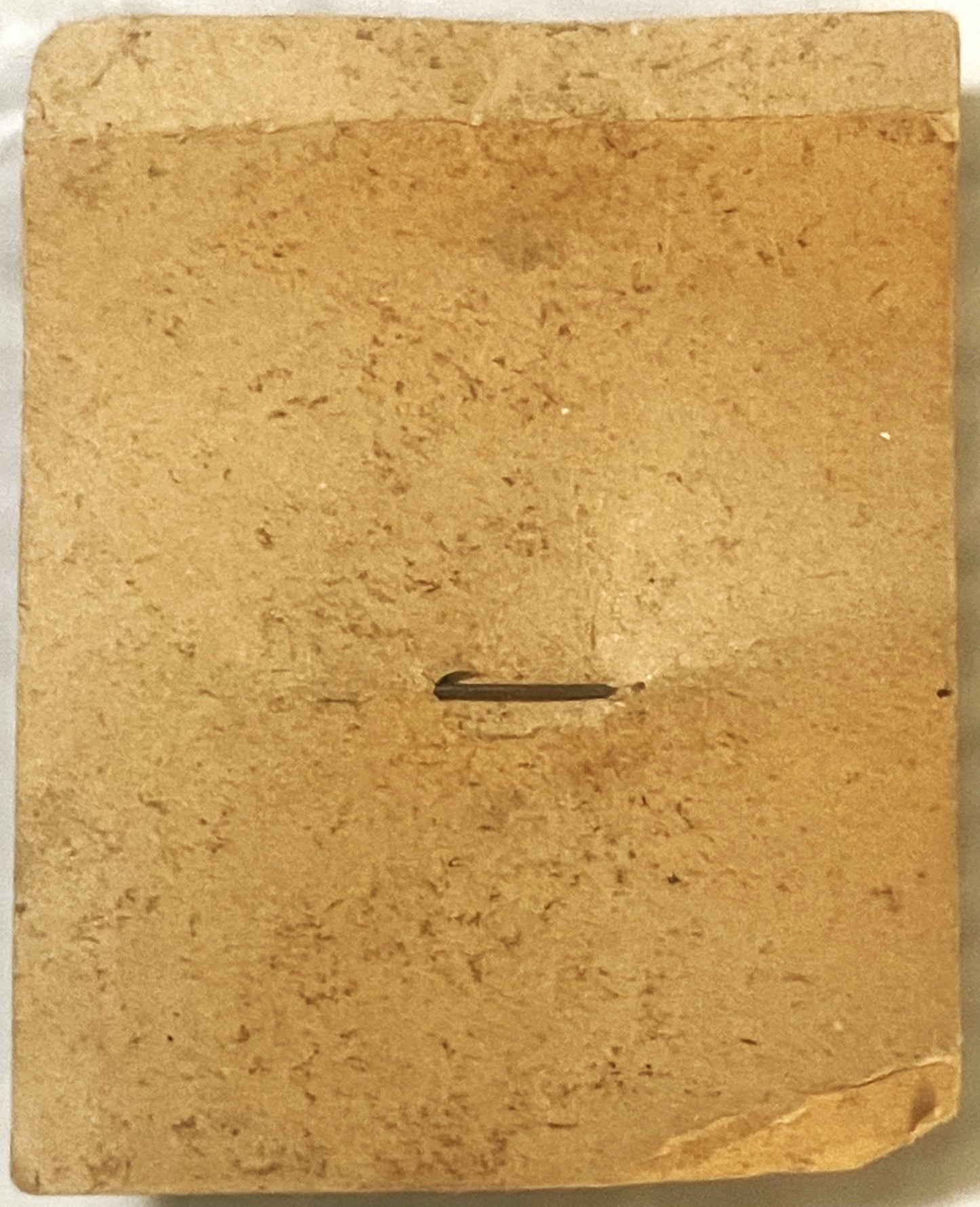 Tan cardboard backing card with slot cutout for vintage tin toy badge, showing wear and creasing