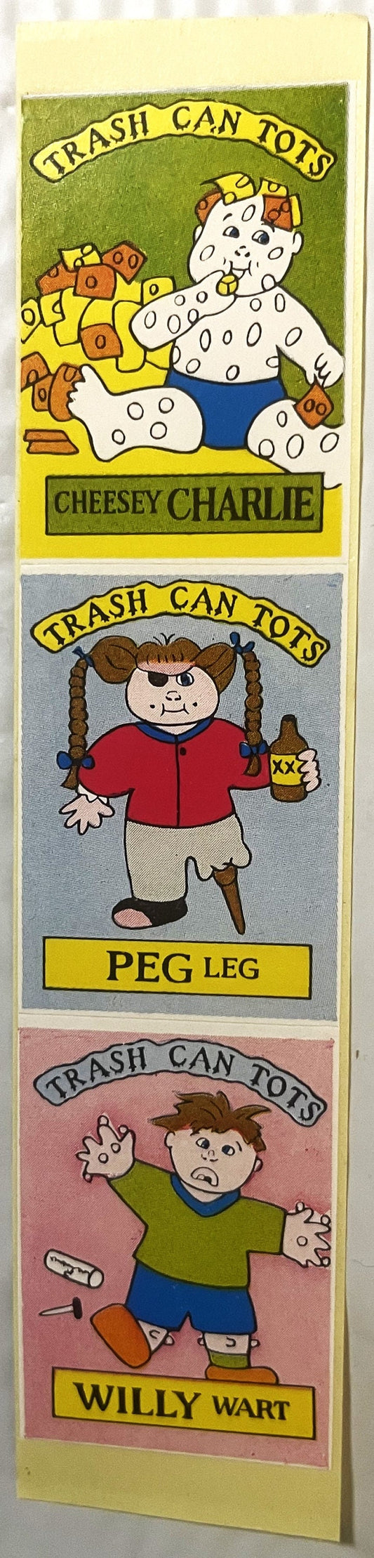 Three stacked sticker cards with cartoon characters labeled Cheesy Charlie, Peg Leg, and Willy Wart, each marked "Trash Can T