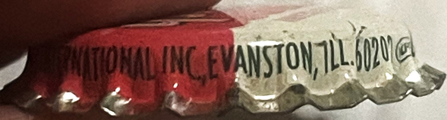 Close-up of red and cream vintage soda bottle cap showing "STRAWBERRY CRUSH" and "EVANSTON, ILL" text, held in hand for scale