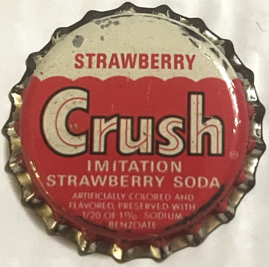 Vintage red and cream Strawberry Crush soda bottle cap with cork lining and crimped metal edges, shown flat from above.