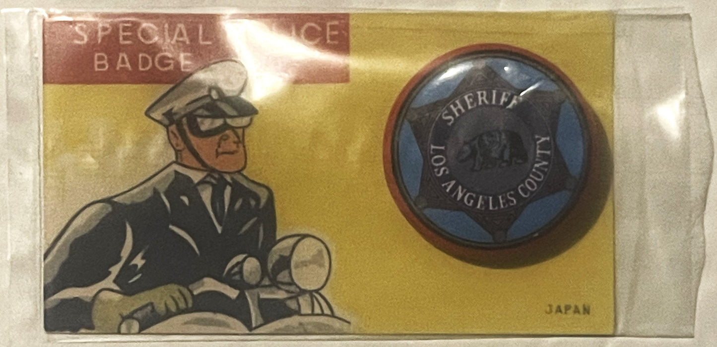 Vintage tin litho card with illustrated sheriff on motorcycle, circular badge showing "Los Angeles County Sheriff" text, gold