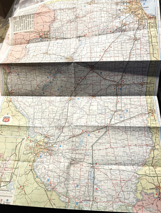 Flat lay of four folded vintage Route 66 maps showing Illinois sections with red and blue highways, town names, and grid patt