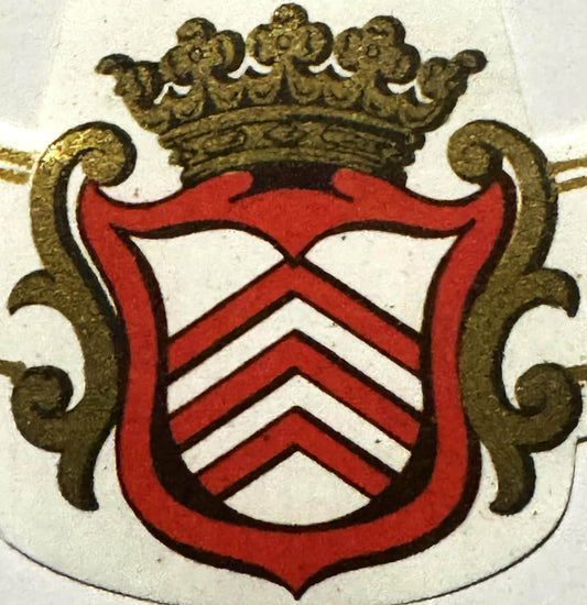 Antique French wine label with red shield bearing white chevron stripes, gold ornamental crown above, and scrolled gold supporters on either side, on cream background.