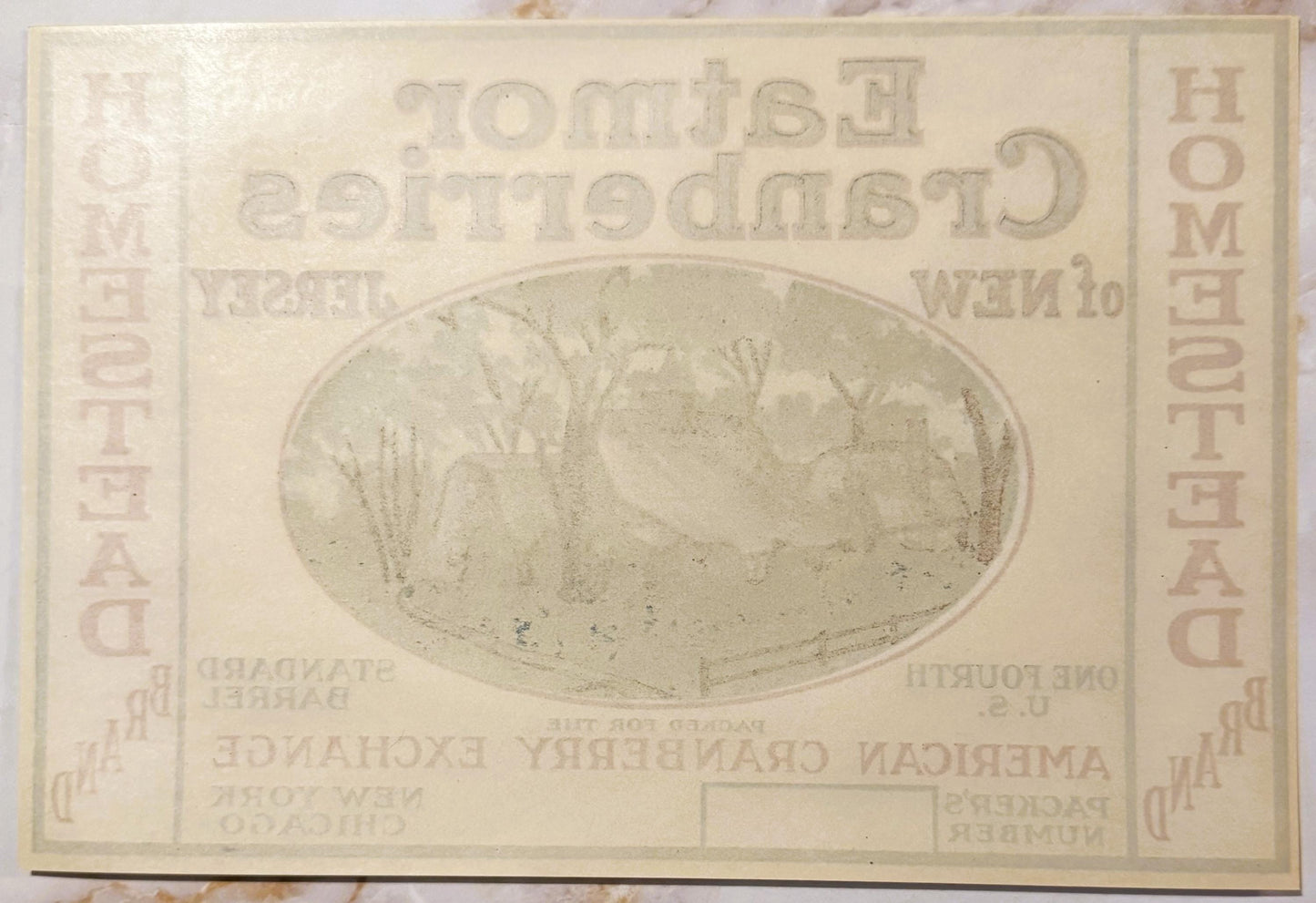 Cream-colored vintage cranberry barrel label with oval landscape illustration and embossed text, showing age spots and wear