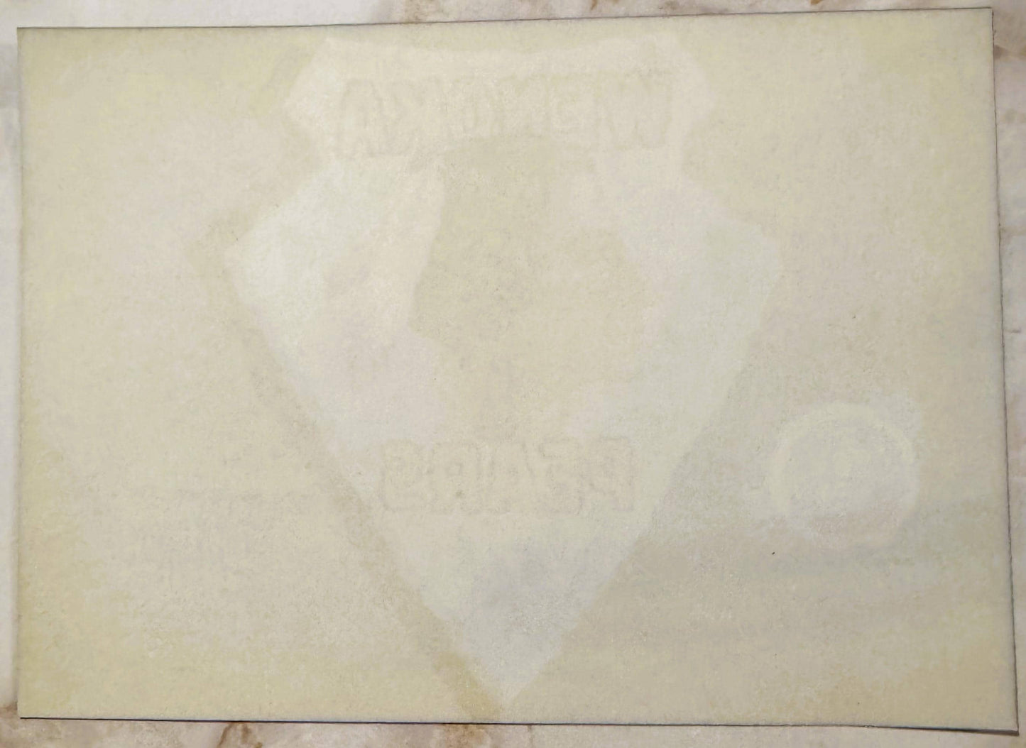 Cream-colored vintage crate label with faint watermark image, showing age spots and wear marks on aged paper