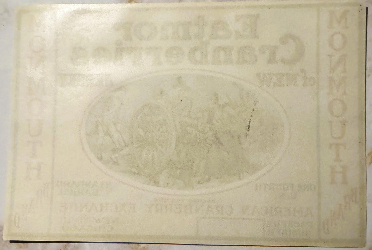 Cream-colored embossed cranberry barrel label featuring oval illustration and text, photographed flat showing wear and age pa