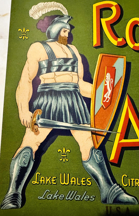 Vintage fruit crate label featuring a bearded warrior in Roman armor and pleated skirt holding a sword, on green background w