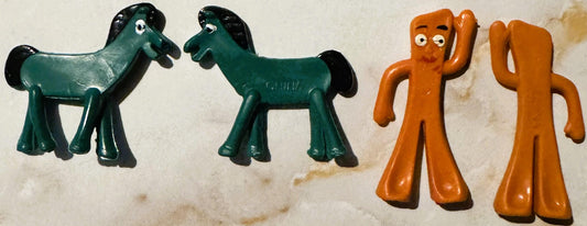 Four vintage bendable vinyl figurines on white background: two green horse-like figures and two orange humanoid figures with