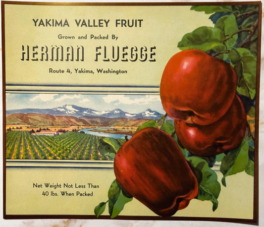 Vintage fruit crate label for Yakima Valley apples by Herman Fluegge, featuring two red apples, mountain landscape, and agric