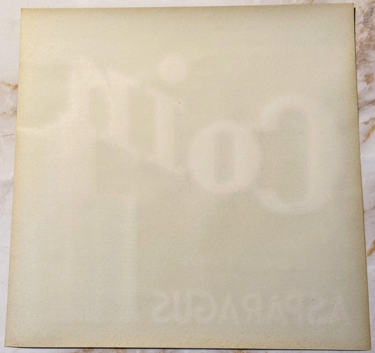 Blank cream-colored vintage crate label with faint watermark text, photographed flat on marble surface