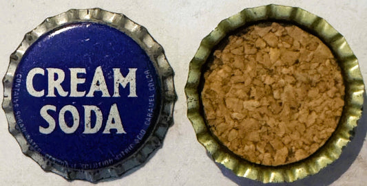Vintage bottle cap showing front and back: blue side reads "CREAM SODA" in white letters, reverse shows cork lining in tan co