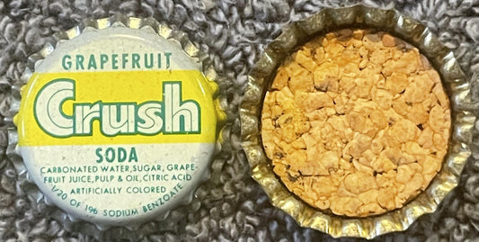 Vintage Grapefruit Crush soda bottle cap showing yellow and white label with cork lining visible on underside, displayed on t