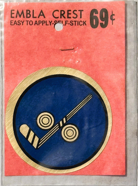 Vintage self-stick emblem crest priced at 69¢, featuring a hockey stick and puck design on blue circle with tan border, on co